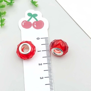 Dettaglio macro di una perla rossa sfaccettata da 14mm con anima in metallo per bracciali DIY