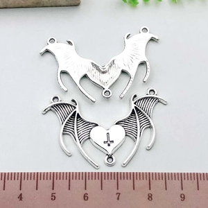 Macro detail of antique silver heart pendant with wings and a scale ruler measurement