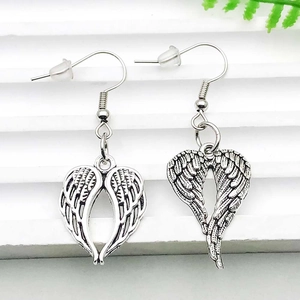 Detail of vintage silver wing earrings with heart silhouette and intricate textures