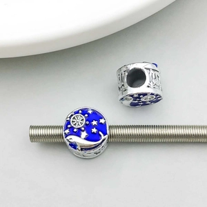 Detail of silver dolphin charm with dark blue enamel and moon star patterns for DIY jewelry