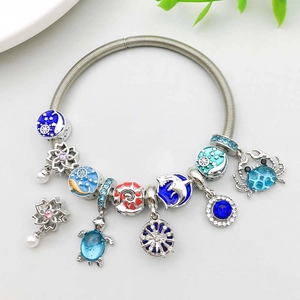 Detail view of a silver marine bracelet with blue enamel shark, turtle, and crab charms