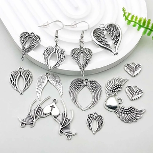 Close-up of vintage silver alloy angel wings and heart charms for DIY jewelry making