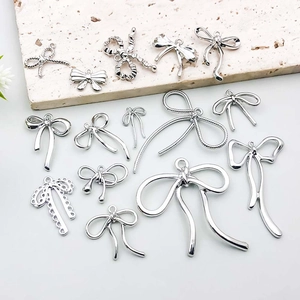 Silver bow pendants collection for DIY jewelry making on a stone display slab