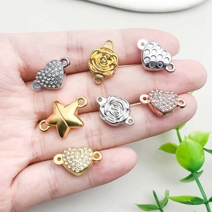 DIY jewelry connectors with rhinestone heart, gold rose, and star charms held in hand