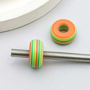 Macro detail of striped resin beads for DIY jewelry making on a metal thread rod