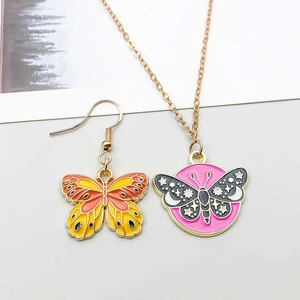 Detailed view of butterfly charm necklace and earrings with colorful enamel dripping finish