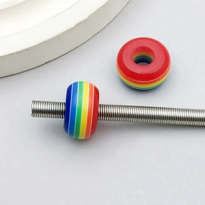 Macro detail of rainbow striped resin beads on a metal charm bracelet rod