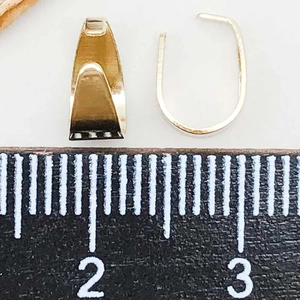 Macro-opname van goudkleurige hanger bails naast een liniaal voor maataanduiding