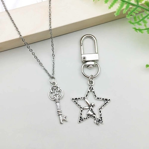 Close-up of vintage silver star fairy keychain and key pendant on white background