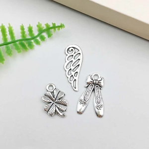 Detailed macro of antique silver alloy charms featuring clover, wing and ballet shoes