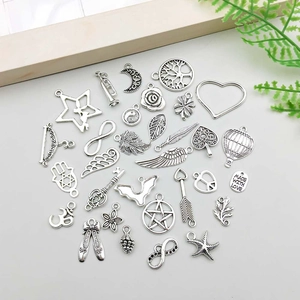 Detailed flat lay of 30 assorted antique silver charms for DIY jewelry making