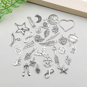 Flat lay of vintage silver alloy charms including tree of life and heart for DIY jewelry