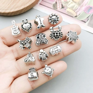 Tredici perle vintage in lega d'argento in varie forme DIY su un vassoio di legno