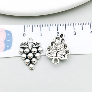 Detailed view of silver alloy grape and Christmas tree charms with measurement scale