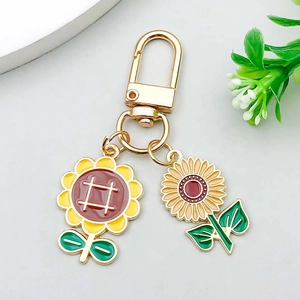 Detailed macro of gold alloy sunflower keychain charms with red oil drip enamel finish