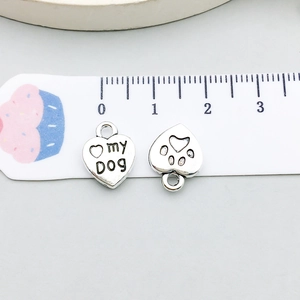Macro view of a silver heart charm with my DOG engraving and hollow paw print detail