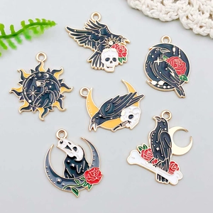 Macro detail of six Gothic raven pendants with enamel skulls and red roses for DIY jewelry
