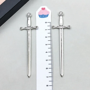 Detailed view of 7.5cm vintage silver sword alloy pendants measured against a ruler scale