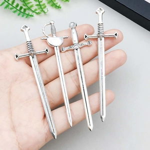 Set of four vintage silver alloy sword pendants with intricate carvings shown in palm