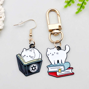 Detailed macro view of cute enamel cat and book charms with bright gold metal plating