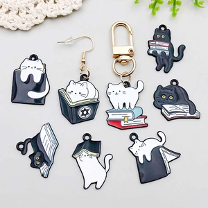 Flat lay of cute enamel cat and books charms for DIY jewelry making with zinc alloy details