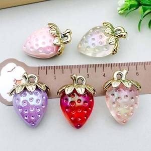 Five colorful acrylic strawberry charms with gold leaves and ruler for size reference