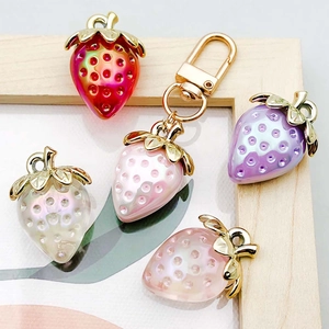 Close-up of colorful acrylic strawberry charms with gold leaf details in a display box