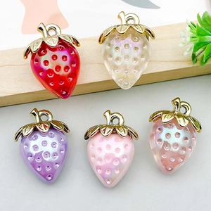 Close-up of five colorful acrylic strawberry charms with gold caps for DIY jewelry