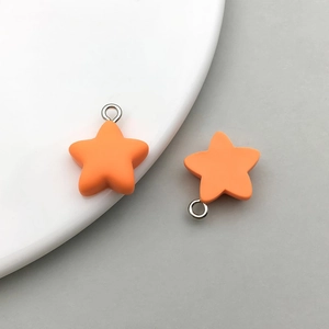 Macro detail of vibrant orange frosted resin star charms with silver metal rings