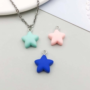 Close-up of matte resin star pendants in mint green, pink, and blue with silver chain