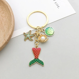 Détail d'un porte-clés doré avec queue de sirène, étoile de mer et coquillage