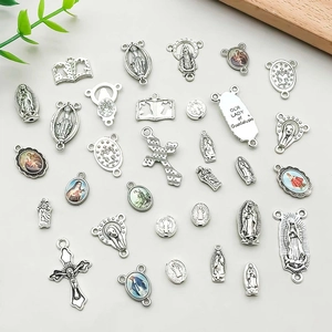 Flat lay detail of assorted silver alloy religious charms including Virgin Mary and crosses