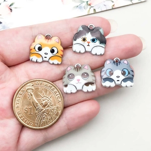 Vue détaillée de pendentifs chats en émail avec pièce de monnaie pour comparaison