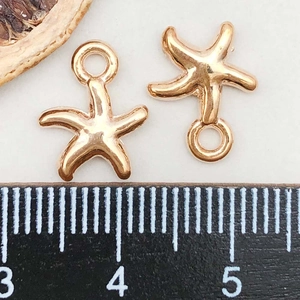Macro shot of KC gold starfish charms showing 1.2cm size measurement on a ruler