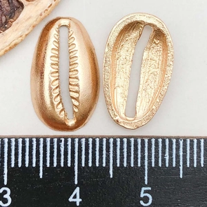 Macro view of KC gold alloy cowrie shell pendants with ruler for size measurement
