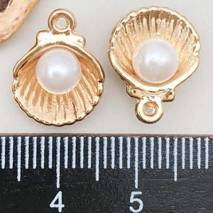 Detailed macro view of rose gold shell pendants with pearls and measurement ruler