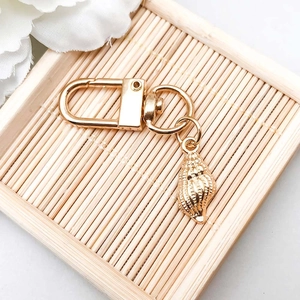 Macro view of gold-plated seashell pendant keychain with fine texture on bamboo tray