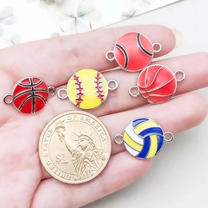 Close-up of colorful enamel sports ball charms in hand for DIY jewelry making