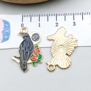 Detailed macro view of black enamel raven and red rose charm with metallic gold backing