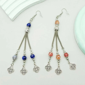 Dettaglio di orecchini boho con nappe d'argento, perline marmorizzate e nodi celtici