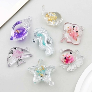 Detalle de colgantes marinos de resina con flores secas y pan de oro para joyería DIY