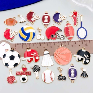 Enameled sports charms featuring soccer and basketball themes on a flat lay with ruler scale