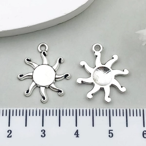 Macro detail of sun-shaped antique silver charms showing textured front and grooved back