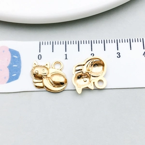 Detailed view of two cat-shaped gold alloy pendants with measurement on a ruler