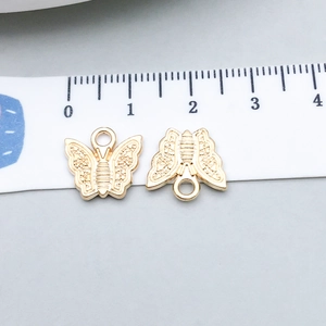 Close-up of golden alloy butterfly charms with dotted texture for DIY jewelry making