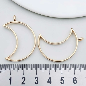 Macro shot of KC gold crescent moon pendant charms with ruler for size measurement