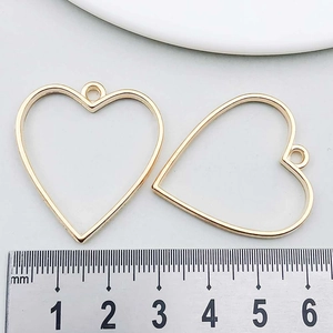Detail of two gold heart-shaped hollow metal alloy pendants for DIY jewelry making