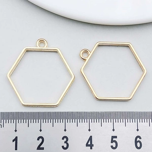 Close-up of golden geometric hexagon frame pendants with measurement ruler for DIY jewelry