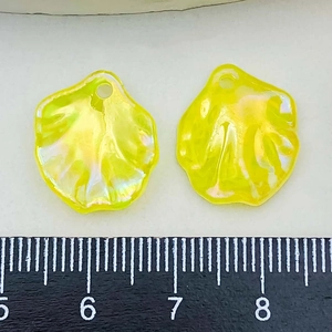 Macro detail of yellow acrylic petal charms showing size with a ruler and pearl luster