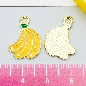 Détail du pendentif banane en émail jaune avec cadre doré à côté d'une règle graduée